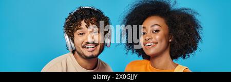 An interracial couple standing together in a studio, wearing headphones, immersed in the music they are listening to. Stock Photo
