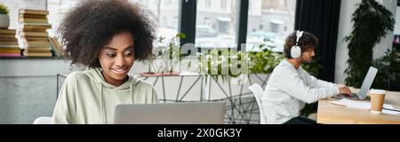 A woman of diverse descent sits in deep thought in front of a laptop computer, immersed in work or study, in a modern coworking space. Stock Photo