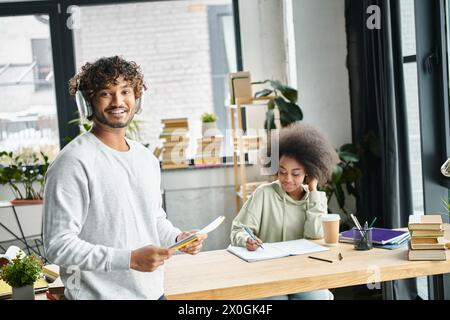 A man and a woman stand side by side at a desk in a modern coworking space, engaged in collaborative study using electronic devices. Stock Photo