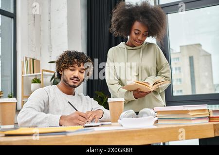 A man and a woman, surrounded by books, engaged in deep study and discussion at a table in a modern coworking space. Stock Photo