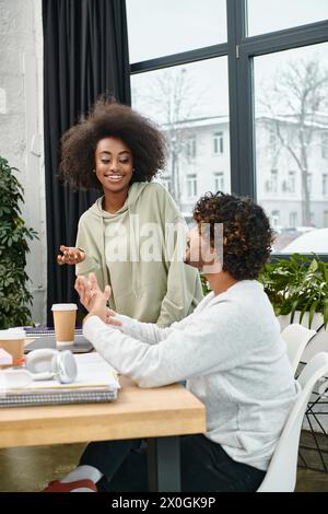 Two multicultural students engrossed in conversation at a modern coworking space. Stock Photo