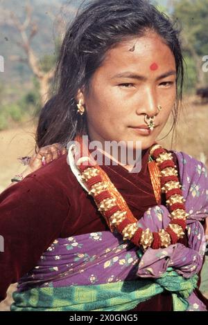 A young Nepalese woman with a painted red dot on her forehead in traditional dress and with a nose ring on a farm near Damauli. [automated translation] Stock Photo