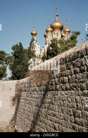 The golden domes of the Russian Orthodox Church of Mary Magdalene behind a wall in Jerusalem. [automated translation] Stock Photo