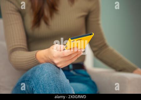 Unrecognizable young woman sitting on a sofa looking at social networks with a smartphone Stock Photo