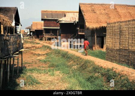 A boy walks over a dam between houses on stilts in Ywama, which was built to connect them. [automated translation] Stock Photo