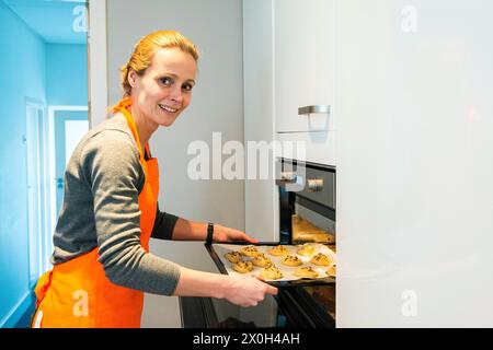 Housewife and Mother Baking Cookies for her Family and Guests. Mid adult caucasian female baking cookies inside her residential, domestic kitchen for ehr family and guests. Kaatsheuvel, Netherlands. MRYES Kaatsheuvel Hoofdstraat Noord-brabant Nederland Copyright: xGuidoxKoppesxPhotox Stock Photo