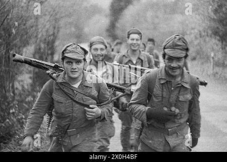 Shouldering the machine gun and laughing mischievously, the group marches along the road. [automated translation] Stock Photo