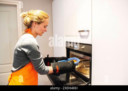 Housewife and Mother Baking Cookies for her Family and Guests. Kaatsheuvel, Netherlands. Mid adult caucasian female removing a fresh baked cake from her heated oven. MRYES Kaatsheuvel Hoofdstraat Noord-brabant Nederland Copyright: xGuidoxKoppesxPhotox Stock Photo
