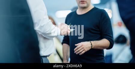 Two businessmen engage in a conversation, exchanging ideas and possibly closing a deal at a conference. Stock Photo