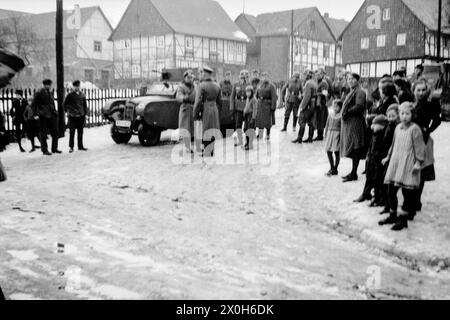 Villagers with soldiers of the Wehrmacht. The vehicle appears to be a passenger car with a machine gun mounted on the roof, but with an imitation of an armored vehicle suspended from the side, similar to the dummy tanks from the Reichswehr era. The picture was probably taken during the preparations for the campaign in France in the winter of 1939/1940 by a member of the 154th Infantry Regiment / 58th Infantry Division in France. [automated translation] Stock Photo