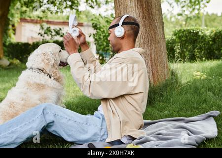 A disabled African American man with myasthenia gravis syndrome sits on the grass next to a loyal Labrador dog. Stock Photo