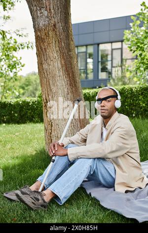 A man with myasthenia gravis sits under a tree, listening to music on headphones Stock Photo
