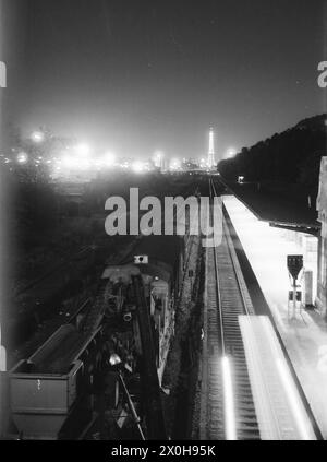 In 1972/1973, the area around Hohenzollerndamm station looked very different from today (2018). The city highway did not yet exist. The freight tracks are derelict, the Ringbahn is still in operation and will fall into a deep sleep in 1980. The radio tower and the main entrance to the exhibition grounds can still be seen, but the ICC did not yet exist. Nevertheless, even back then everything was already aglow with lights. An S-Bahn train has just left the station in the direction of Heidelberger Platz. A Reichsbahn construction train is standing on one of the freight tracks. [automated Stock Photo