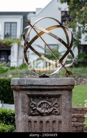 Brass or bronze large scale armillary sundial sphere with raised roman numerals and arrow directional on plinth, stone pedestal with pattern. Hotel ba Stock Photo