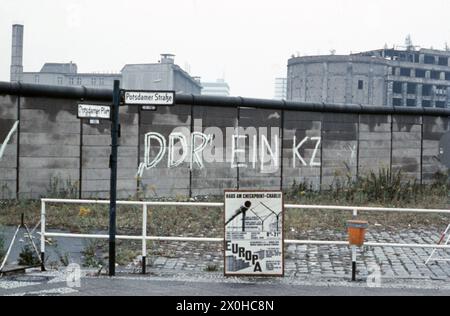 'A graffiti with the statement ''GDR a concentration camp'' on the Berlin Wall at Potsdamer Platz. The poster in the foreground reads ''Europa-Haus at Checkpoint Charlie''.' Stock Photo