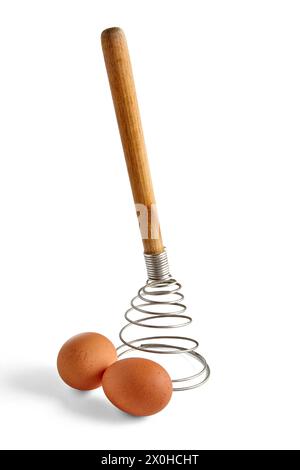 Two beige chicken eggs and a spiral metal whisk are isolated on a white background Stock Photo