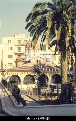 Greek Orthodox church, built on an old Greek temple. A palm tree in front, the church behind [automated translation] Stock Photo