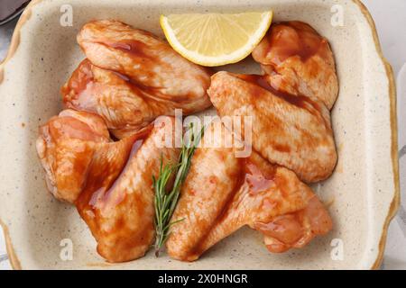 Raw marinated chicken wings, rosemary and lemon in baking dish on table, top view Stock Photo