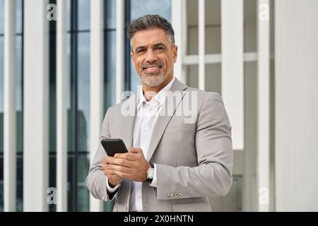 Confident happy middle aged business man outdoors using smartphone. Portrait Stock Photo