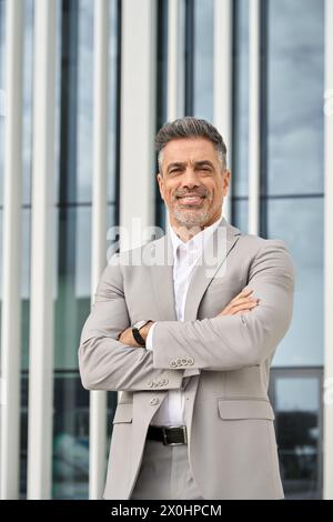 Happy mature business man wearing suit standing outdoor. Vertical portrait. Stock Photo