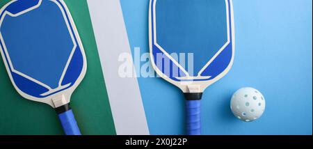 Blue wooden pickleball paddles and a white ball on playing court. Top view. Stock Photo