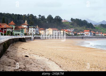 A group of individuals walking along a sandy beach in Ribadesella, Asturias, Spain. The group is strolling casually, enjoying the seaside scenery on a Stock Photo