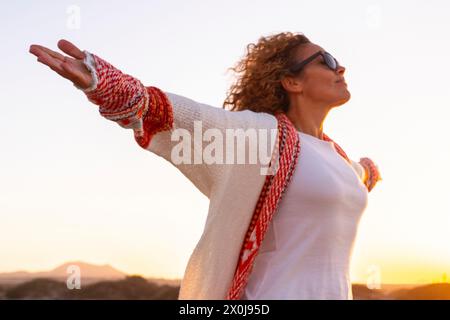 Inner balance and happiness concept with young woman opening arms and outstretching admiring and enjoying a beautiful sunset in the desert nature. Travel and enjoy life people. Freedom destination Stock Photo