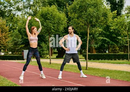 A determined man and woman in sportswear, train together on a track, showcasing motivation and teamwork. Stock Photo