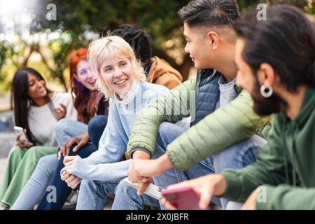 A multicultural group of university students enjoys a lively discussion and shared laughter in an outdoor campus - Friends gathering together, youthfu Stock Photo
