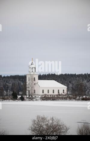 Small white church on a frozen lake in a cold winter landscape with snow and ice. Varviks kyrka, Sweden Stock Photo