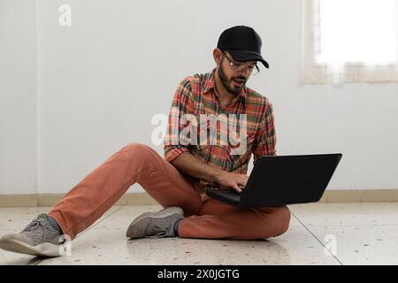 Latin American man with his laptop computer is a programmer and specializes in web development. Stock Photo