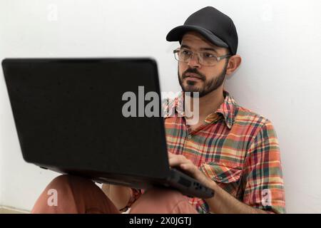 Latin American man with his laptop computer is a programmer and specializes in web development. Stock Photo