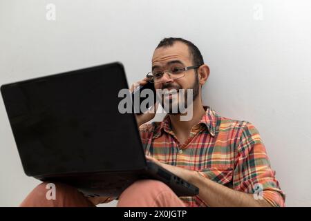 Latin American man with his laptop computer is a programmer and specializes in web development. Stock Photo