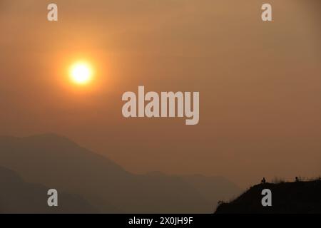 Last sunset of Nepali Year 2080 BS A man sits on the edge of a cliff as the sun sets against the hills surrounding Kathmandu Valley on Nepali new year eve on 12 April, 2024. Nepal on 13 April, 2024 celebrate the new year 2081 BS with grandeur and fervor. Copyright: xSubashxShresthax Stock Photo