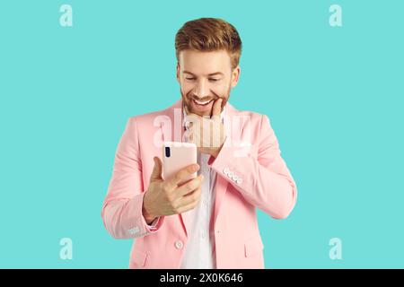 Astonished stylish young man holding smartphone and looking at it Stock Photo