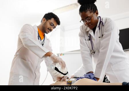 A couple of medical professionals are carefully performing a procedure on a patient in a hospital setting. Stock Photo