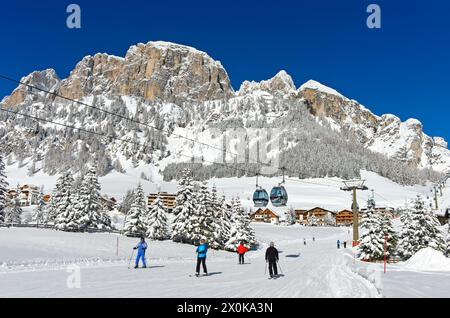 Skiers on the descent to the valley station of the Colfosco cable car, Colfosco, Corvara, Alta Badia winter sports region, Dolomites, South Tyrol, Italy Stock Photo