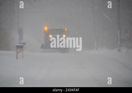 Large snow plow on on stormy winter road in a blizzard snowstorm December, Yarmouth, Maine, USA Stock Photo
