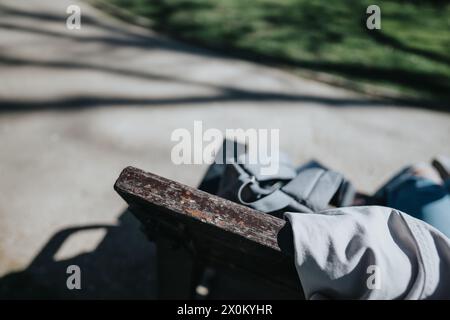 Student resting on a bench in outdoor park with backpack Stock Photo
