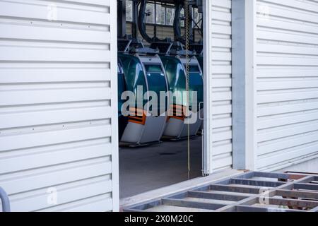 View of gondola lift cabins stored inside a large industrial building with white exterior walls. Stock Photo