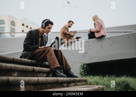 Young professionals working on laptops outdoors on urban steps Stock Photo