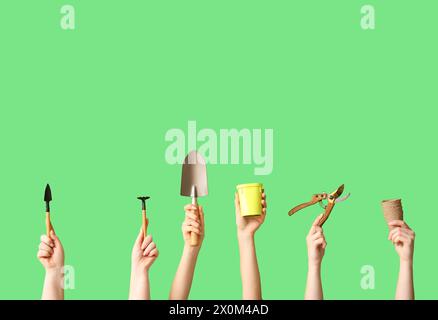 Female hands with different gardening tools on green background Stock Photo