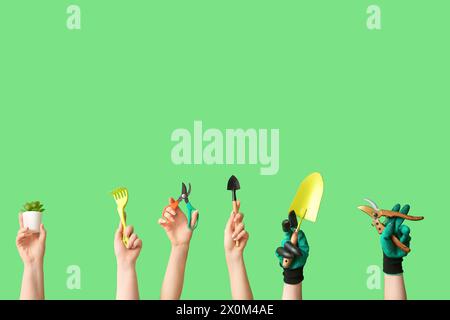 Female hands with different gardening tools on green background Stock Photo