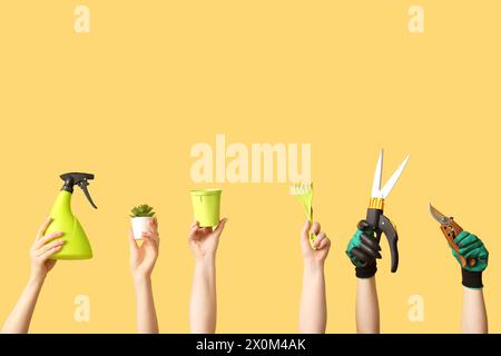 Female hands with different gardening tools on yellow background Stock Photo