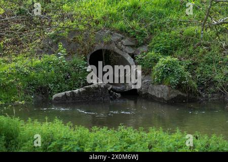 Abwasserkanal aus Beton führt Wasser in einen kleine Bach Stock Photo