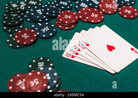 Casino poker gambling and winning combination. Royal flush and a bet of chips on a green table background Stock Photo