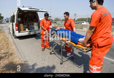 Group of paramedic or emergency medical technician (EMT) in orange uniform helping neck and head accident victim lying on stretcher long spinal board. Stock Photo