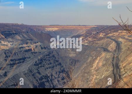 Huge iron ore quarry with working dump trucks and excavators Stock Photo