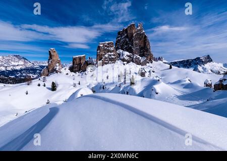 Snowdrift creating artful structures in winter, snow-covered slopes of alpine Dolomite landscape and summits of the Cinque Torri group in the distance Stock Photo