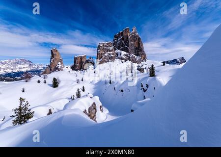 Snowdrift creating artful structures in winter, snow-covered slopes of alpine Dolomite landscape and summits of the Cinque Torri group in the distance Stock Photo